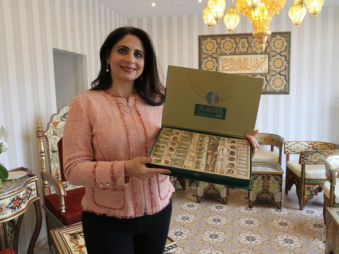 Frau hält Geschenkbox mit orientalischen Süßwaren in einem Café